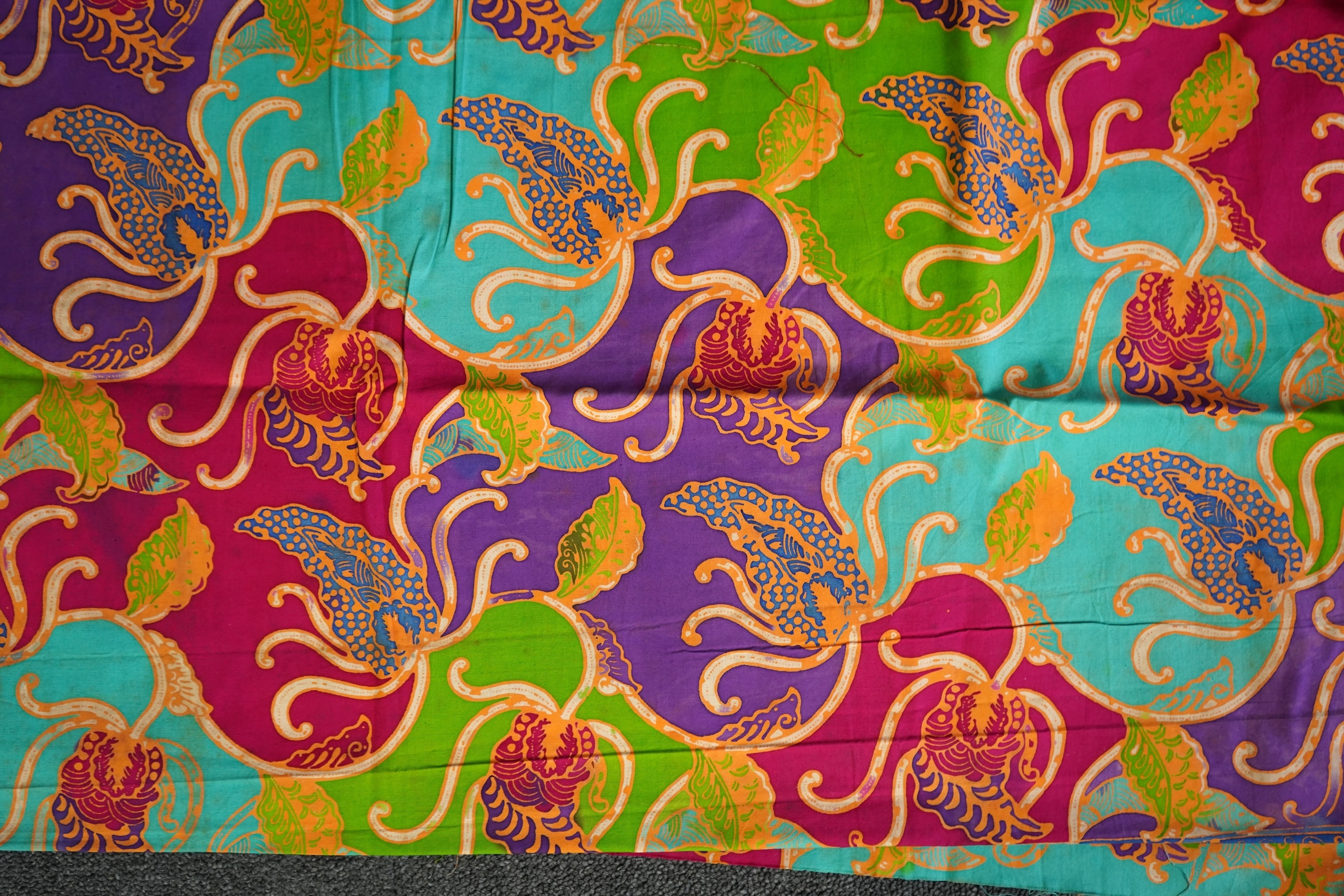 A large Indian silk embroidered and mirrored temple pelmet, with a cerise silk embroidered hanging and a length of cotton wax resist style printed fabric. Temple pelmet 468cm long x 70cm, deep. Condition - the pelmet has